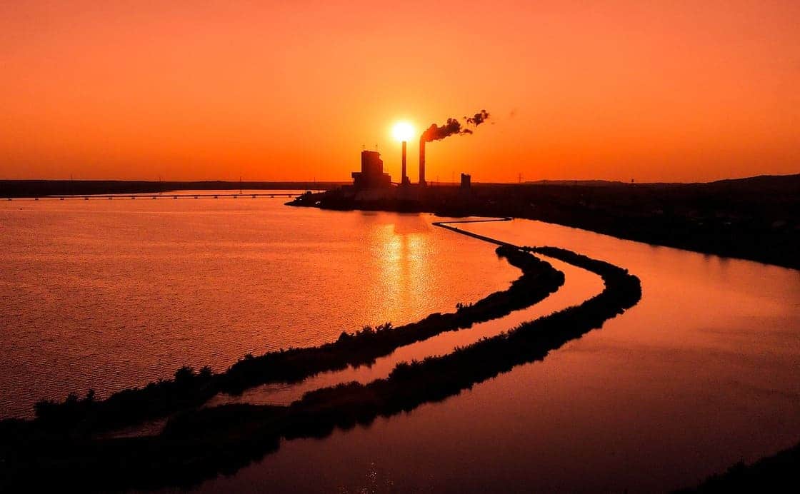 Coucher de soleil sur une usine, illustration du réchauffement climatique